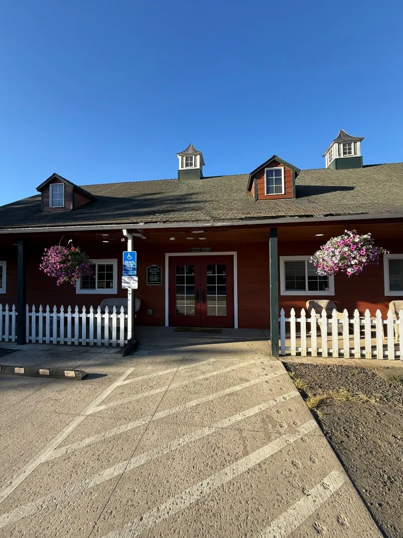 The clinic entrance with hanging flower baskets and a white picket fence