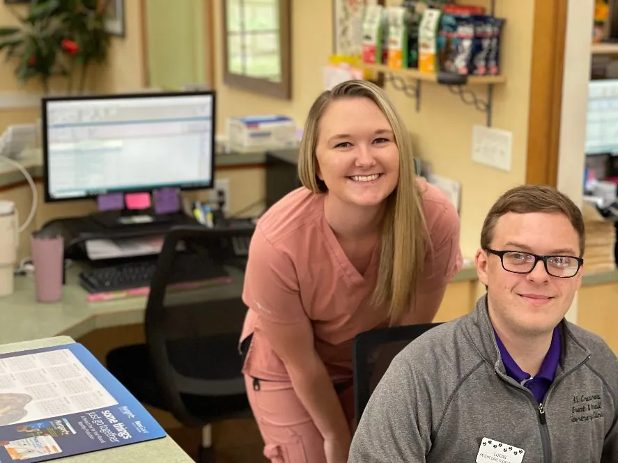 Two smiling team members at the front desk